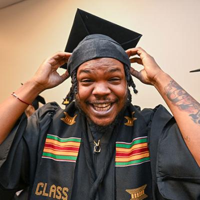 GGC graduate smiling while adjusting cap