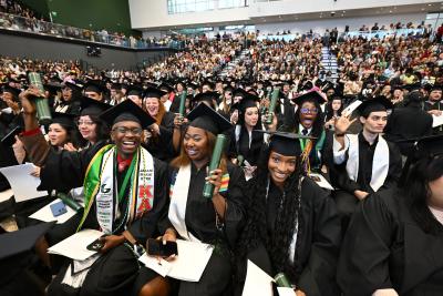 spring 2025 graduates cheering and holding diplomas at commencement ceremony