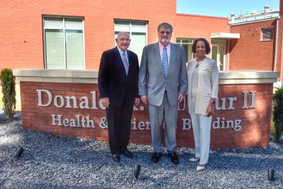 University System of Georgia Chancellor Dr. Sonny Perdue, Donald Balfour II and Georgia Gwinnett College President Jann L. Joseph stand in front of new building signage