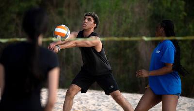 Student serving the ball during a sand volleyball game
